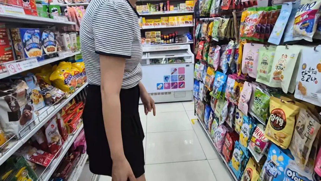 A shopper choosing Korean snacks from a colorful snack aisle at Daiso.