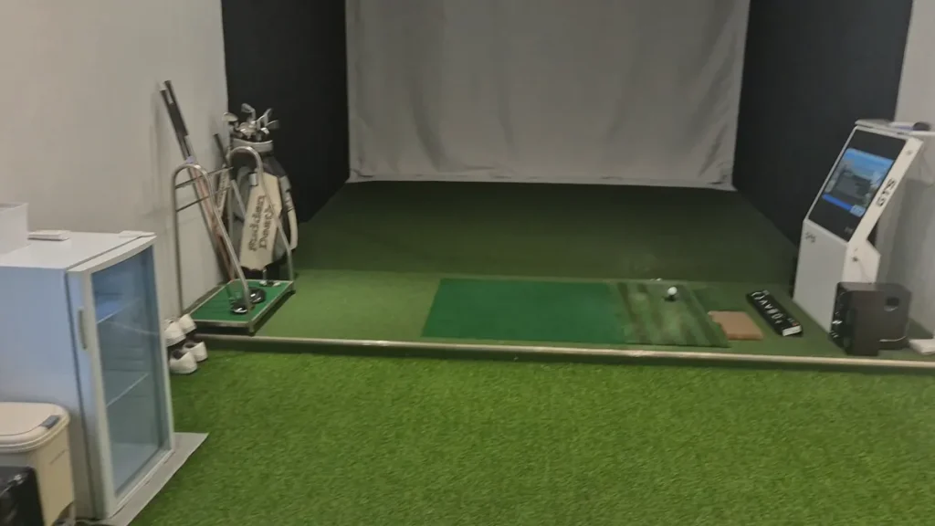 A screen golf room inside a Korean pension with golf clubs and a practice area.